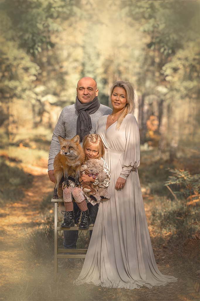 Portret rodziny - Mama, Tata i dziewczynka. Stojących na drodze w lesie. Mama w białej lejącej się sukni, obok drabinka z siedzącą na niej dziewczynką i lisem.