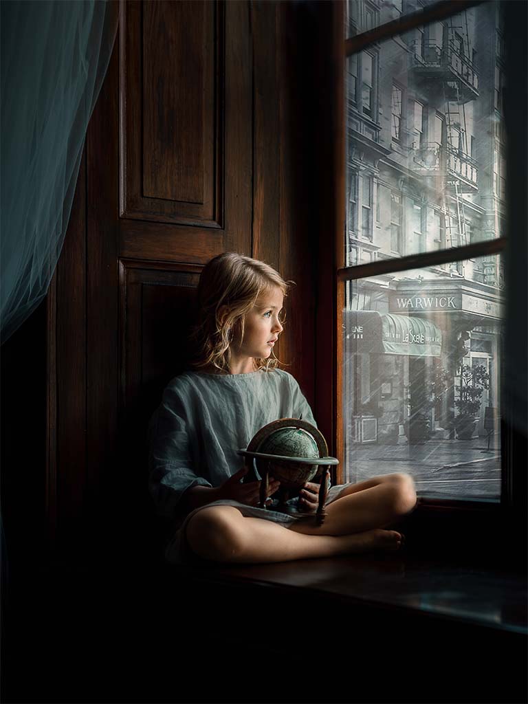 dziewczynka siedząca na parapecie z globusem na kolanach patrząca przez okno na ulicę