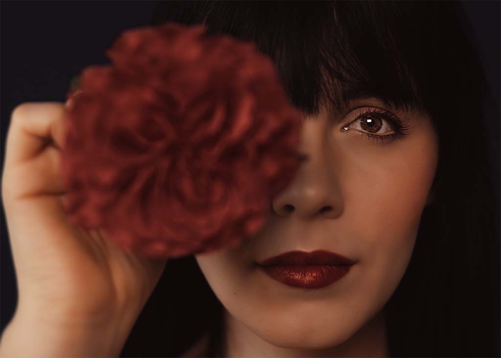 portret twarzy kobiety w połowie zasłonięty kwiatami