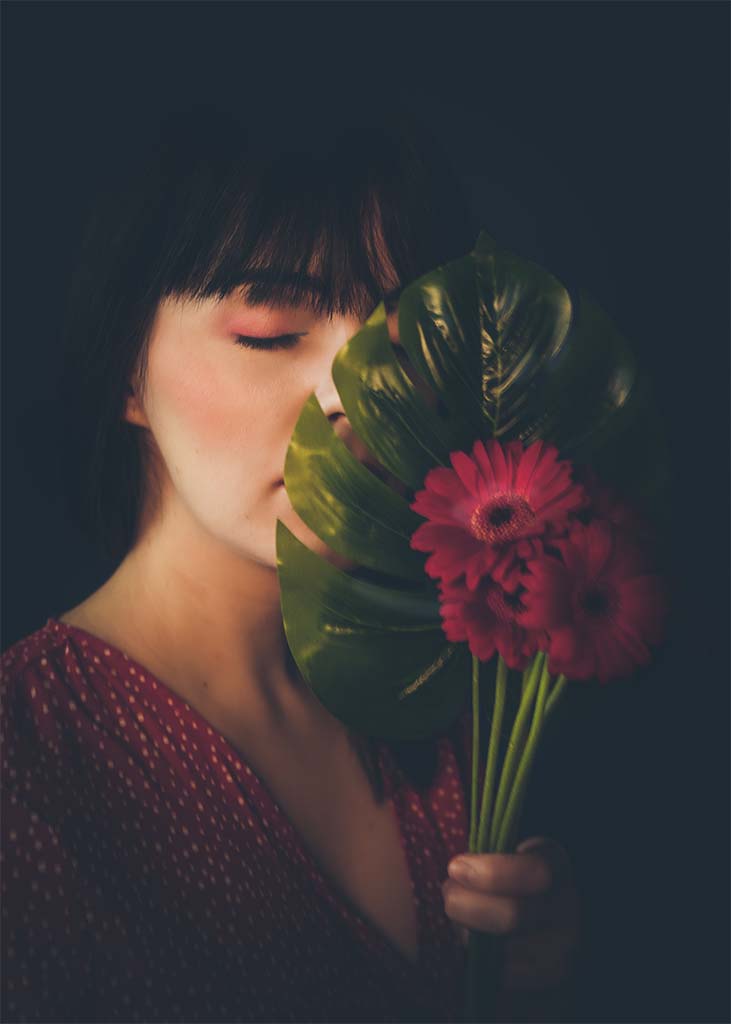 portret twarzy kobiety w połowie zasłonięty kwiatami