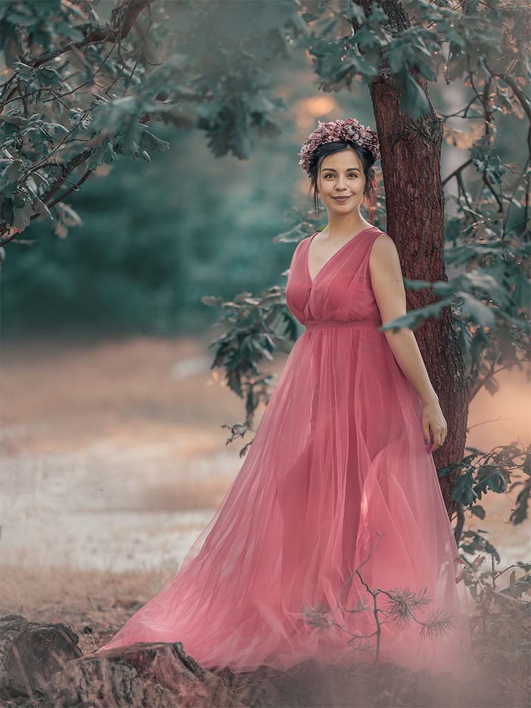 kobieta w różowej sukni stojąca pod drzewem